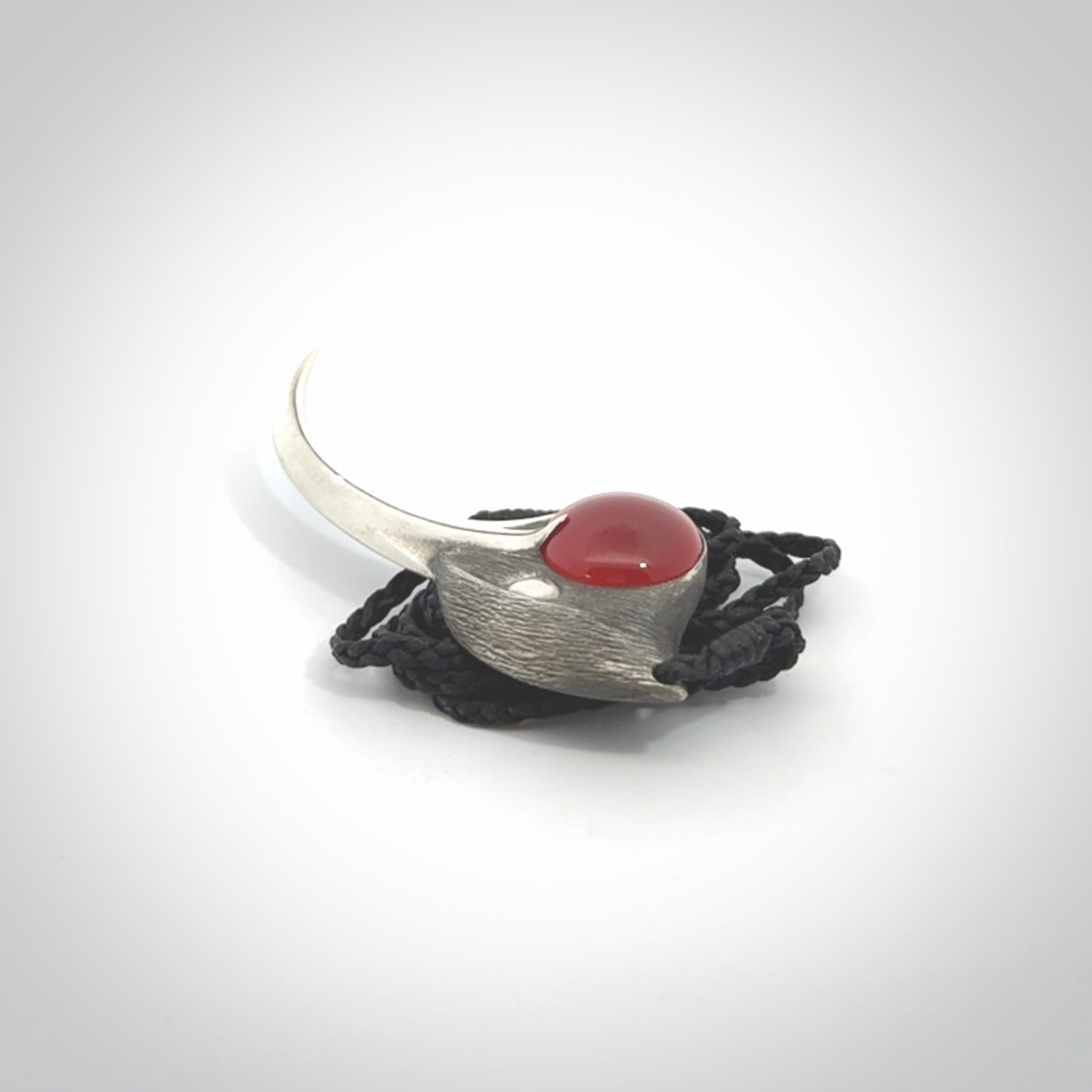 This is a hand carved Sterling Silver Huia bird pendant with Red Cats Eye insert. This is a large sized necklace and is provided with an adjustable black cord.
