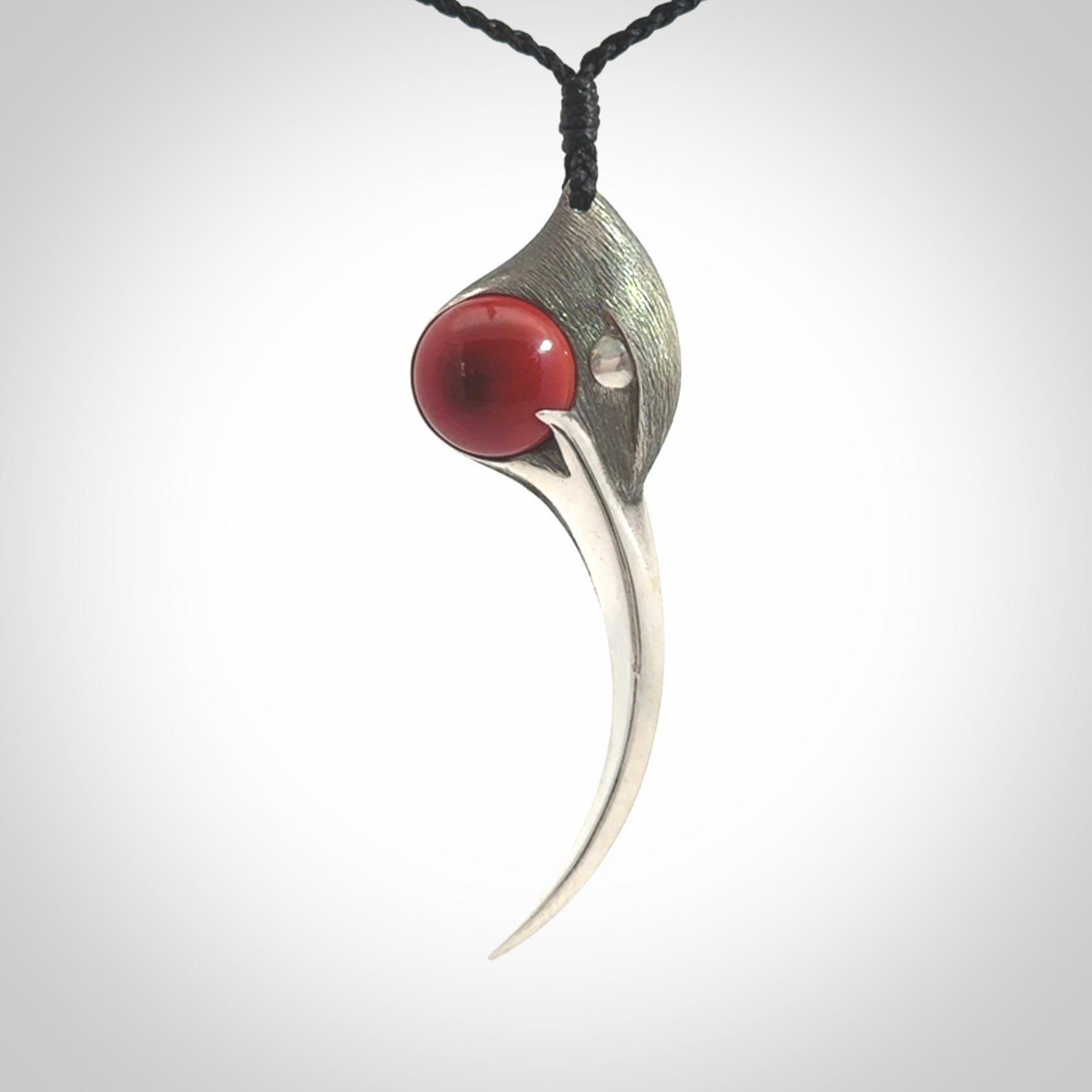 This is a hand carved Sterling Silver Huia bird pendant with Red Cats Eye insert. This is a large sized necklace and is provided with an adjustable black cord.