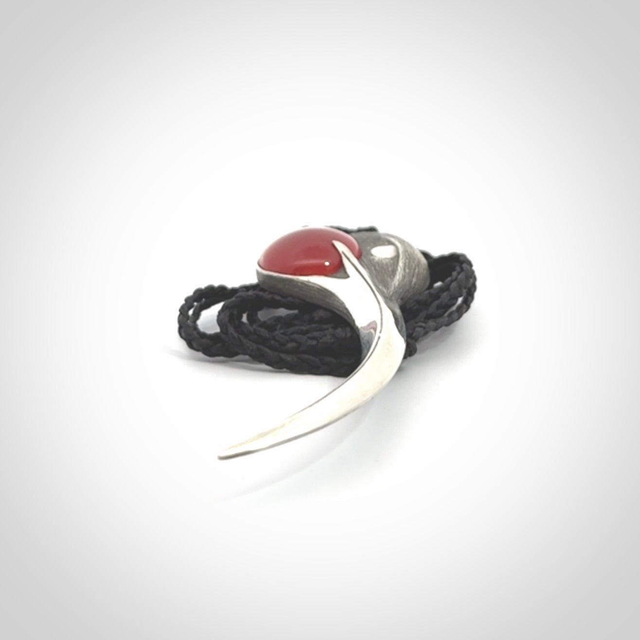This is a hand carved Sterling Silver Huia bird pendant with Red Cats Eye insert. This is a large sized necklace and is provided with an adjustable black cord.