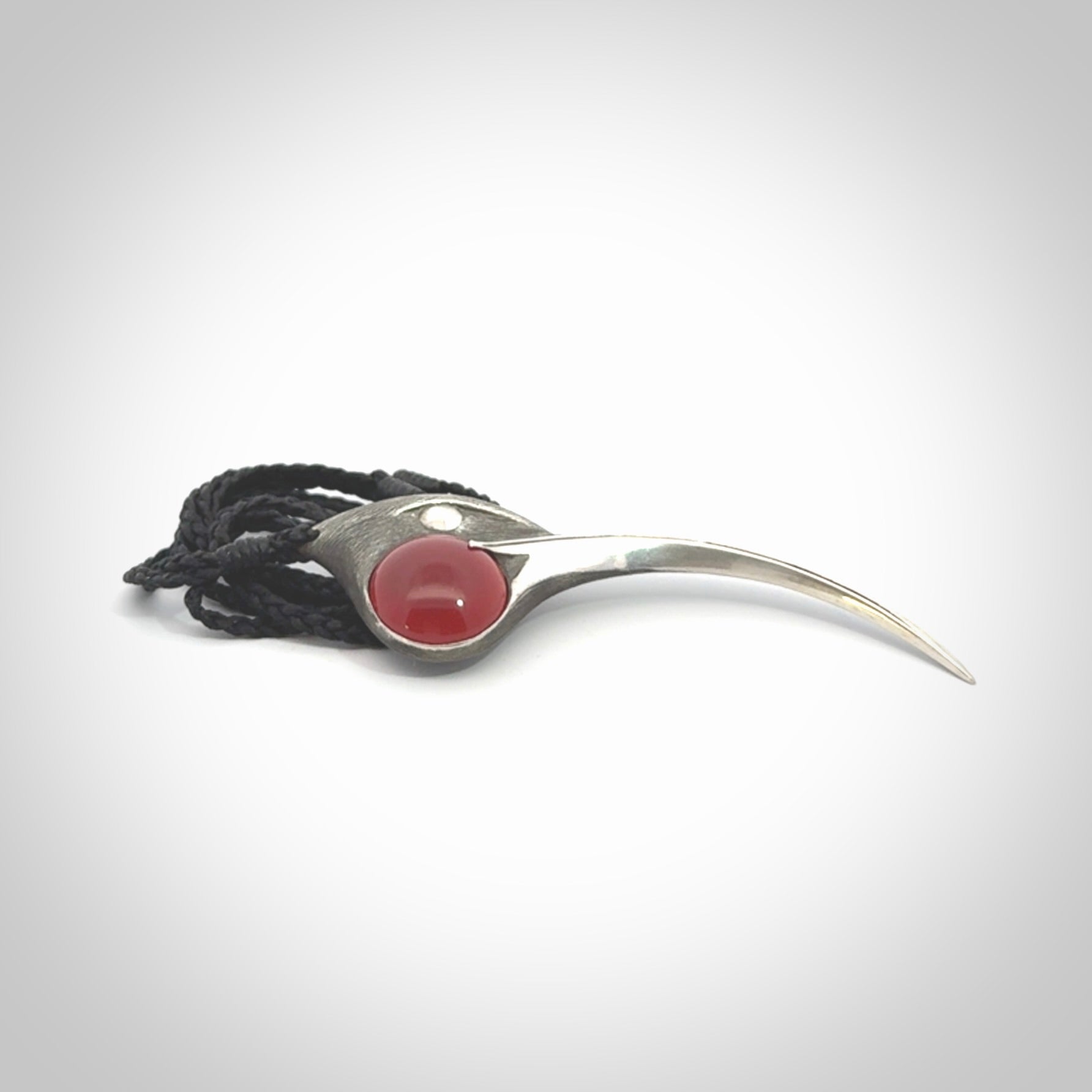 This is a hand carved Sterling Silver Huia bird pendant with Red Cats Eye insert. This is a large sized necklace and is provided with an adjustable black cord.