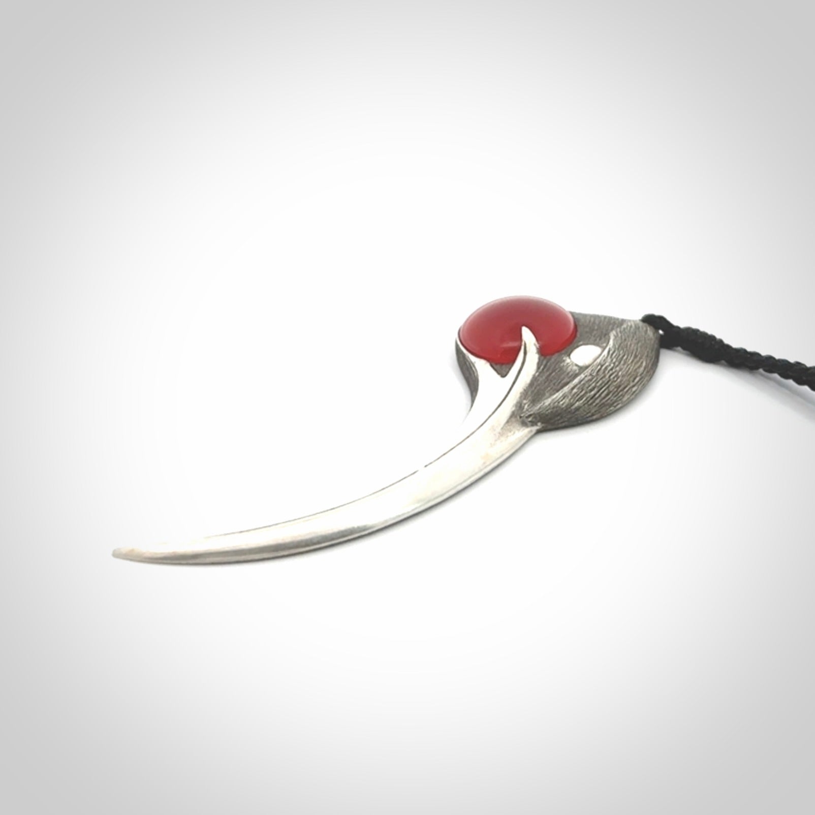 This is a hand carved Sterling Silver Huia bird pendant with Red Cats Eye insert. This is a large sized necklace and is provided with an adjustable black cord.