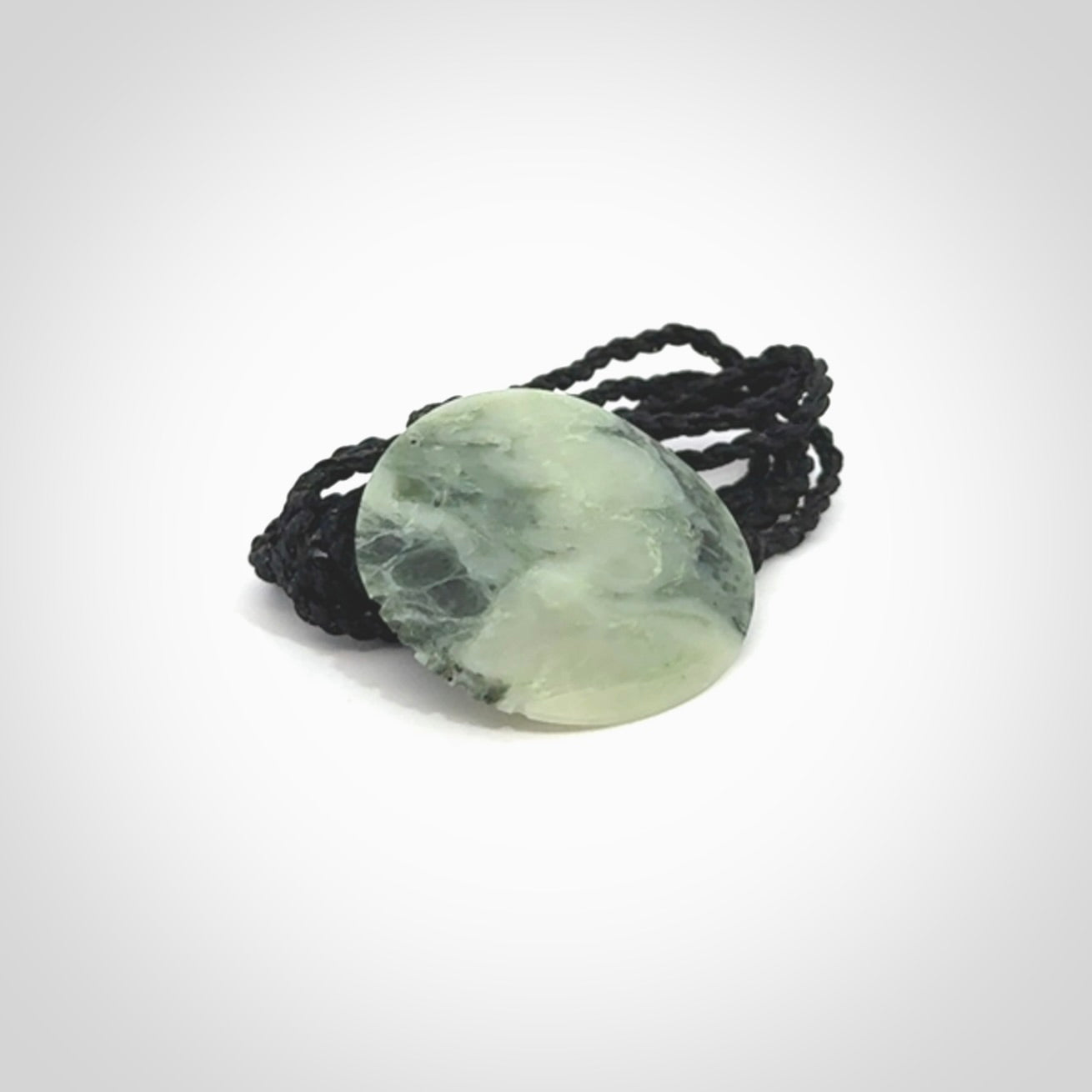 This piece is a small oval round, disc pendant hand carved in New Zealand jade.
