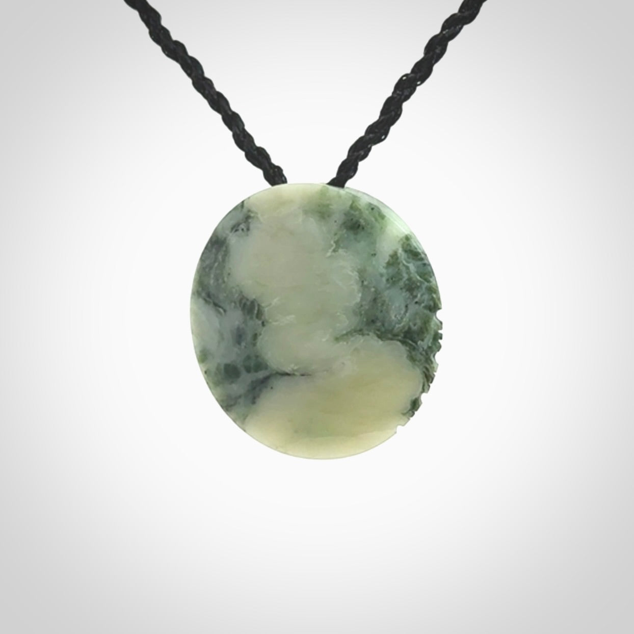 This piece is a small oval round, disc pendant hand carved in New Zealand jade.