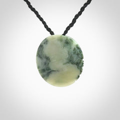 This piece is a small oval round, disc pendant hand carved in New Zealand jade.