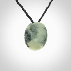 This piece is a small oval round, disc pendant hand carved in New Zealand jade.