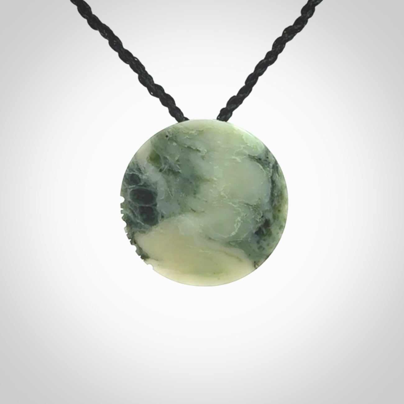 This piece is a small oval round, disc pendant hand carved in New Zealand jade.