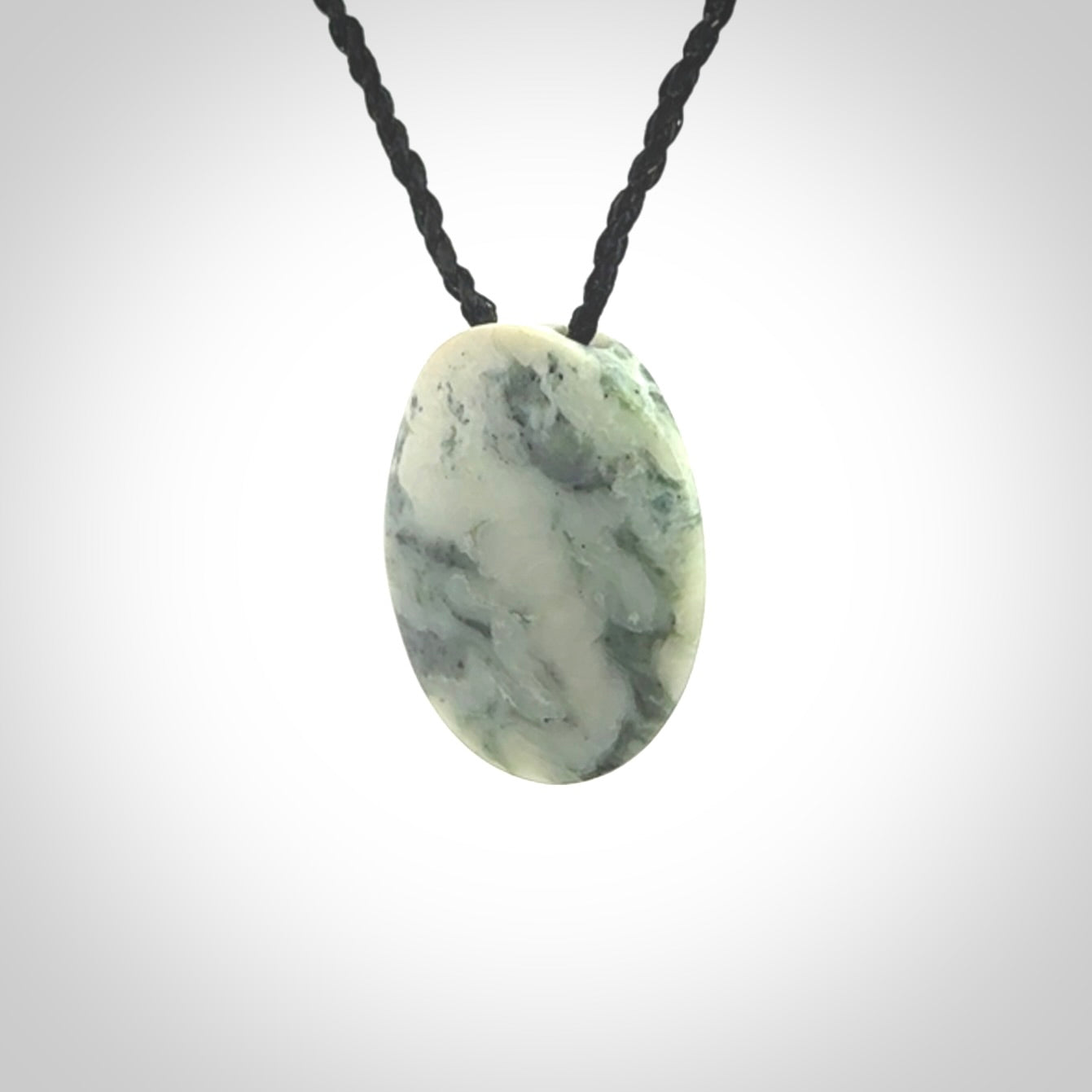 This piece is a small oval round, disc pendant hand carved in New Zealand jade.