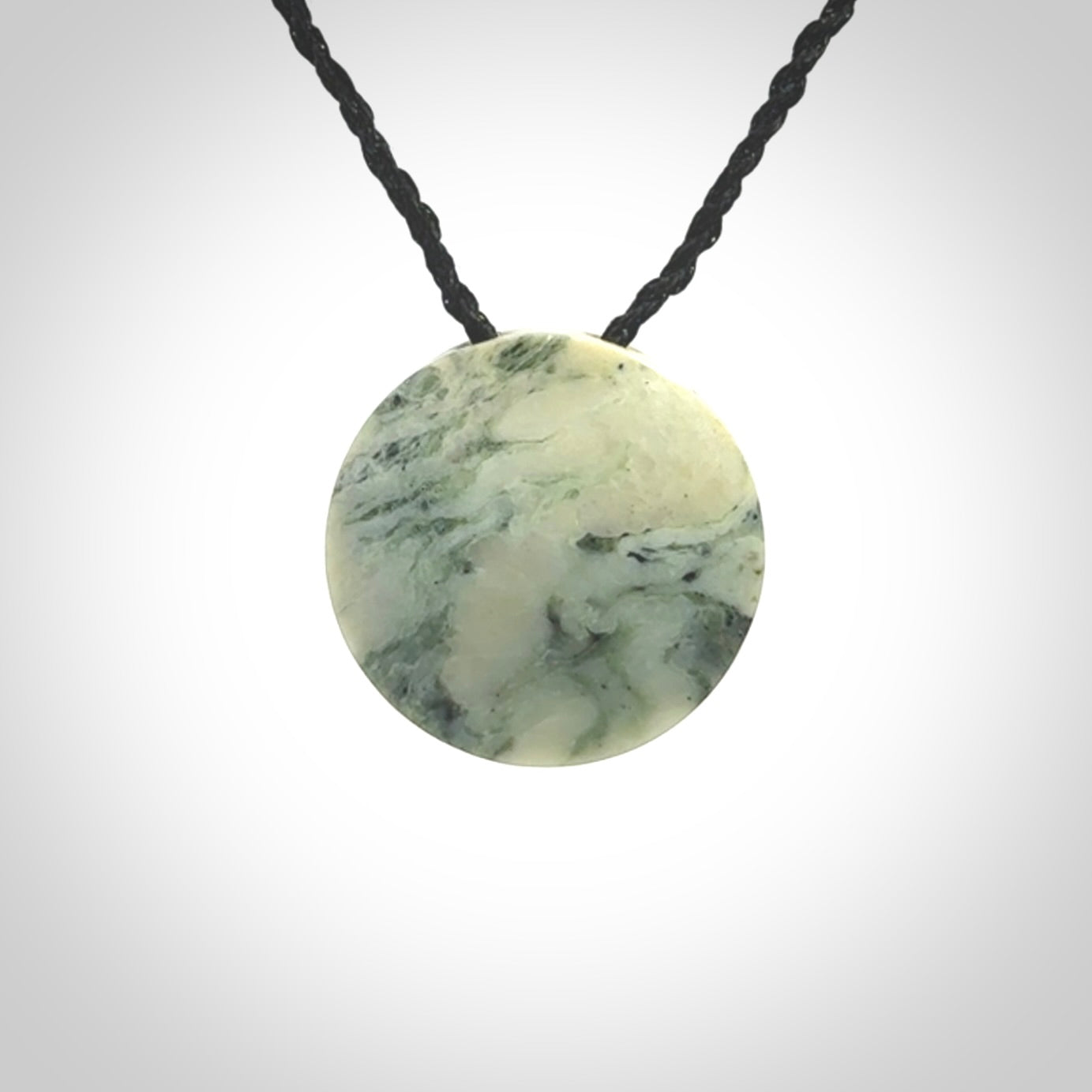 This piece is a small oval round, disc pendant hand carved in New Zealand jade.