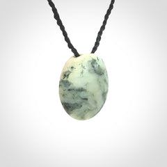 This piece is a small oval round, disc pendant hand carved in New Zealand jade.