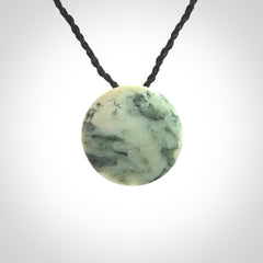 This piece is a small oval round, disc pendant hand carved in New Zealand jade.