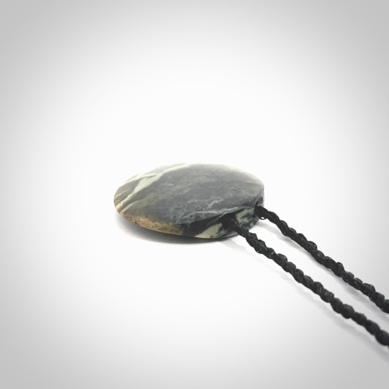 This piece is a small oval round, disc pendant hand carved in New Zealand jade.