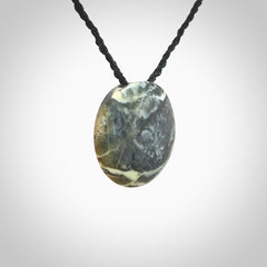 This piece is a small oval round, disc pendant hand carved in New Zealand jade.