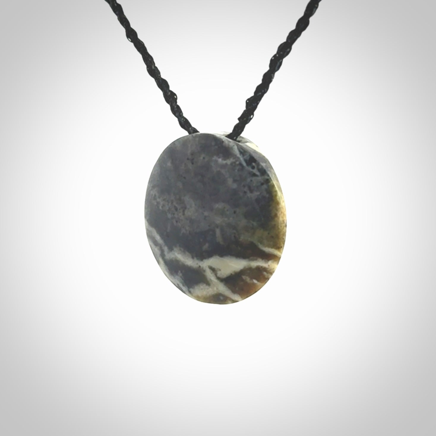 This piece is a small oval round, disc pendant hand carved in New Zealand jade.