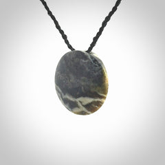 This piece is a small oval round, disc pendant hand carved in New Zealand jade.