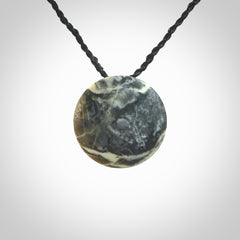This piece is a small oval round, disc pendant hand carved in New Zealand jade.