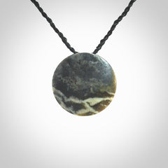 This piece is a small oval round, disc pendant hand carved in New Zealand jade.