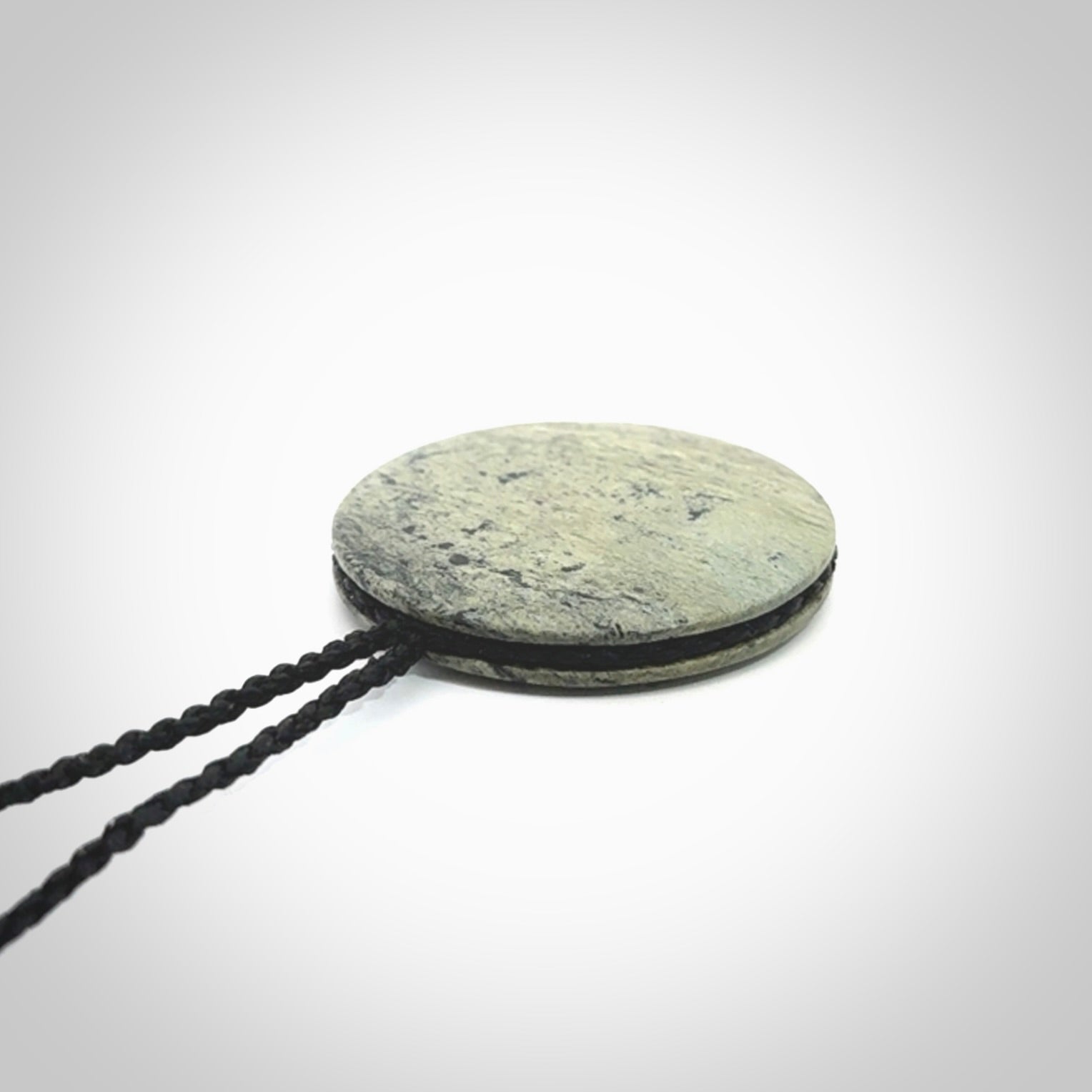 This piece is a contemporary disc pendant hand carved in New Zealand jade.