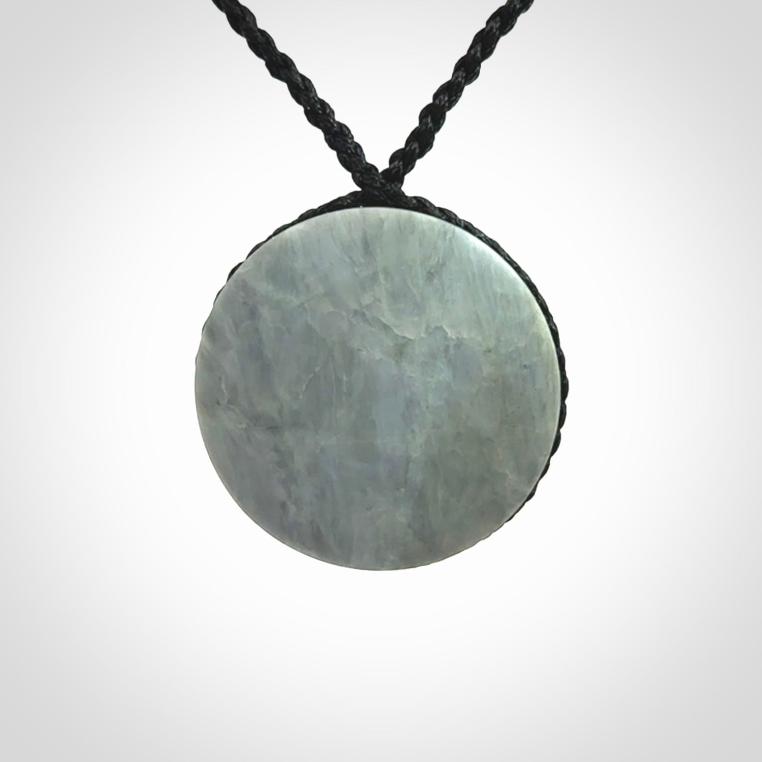 This piece is a contemporary disc pendant hand carved in New Zealand jade.