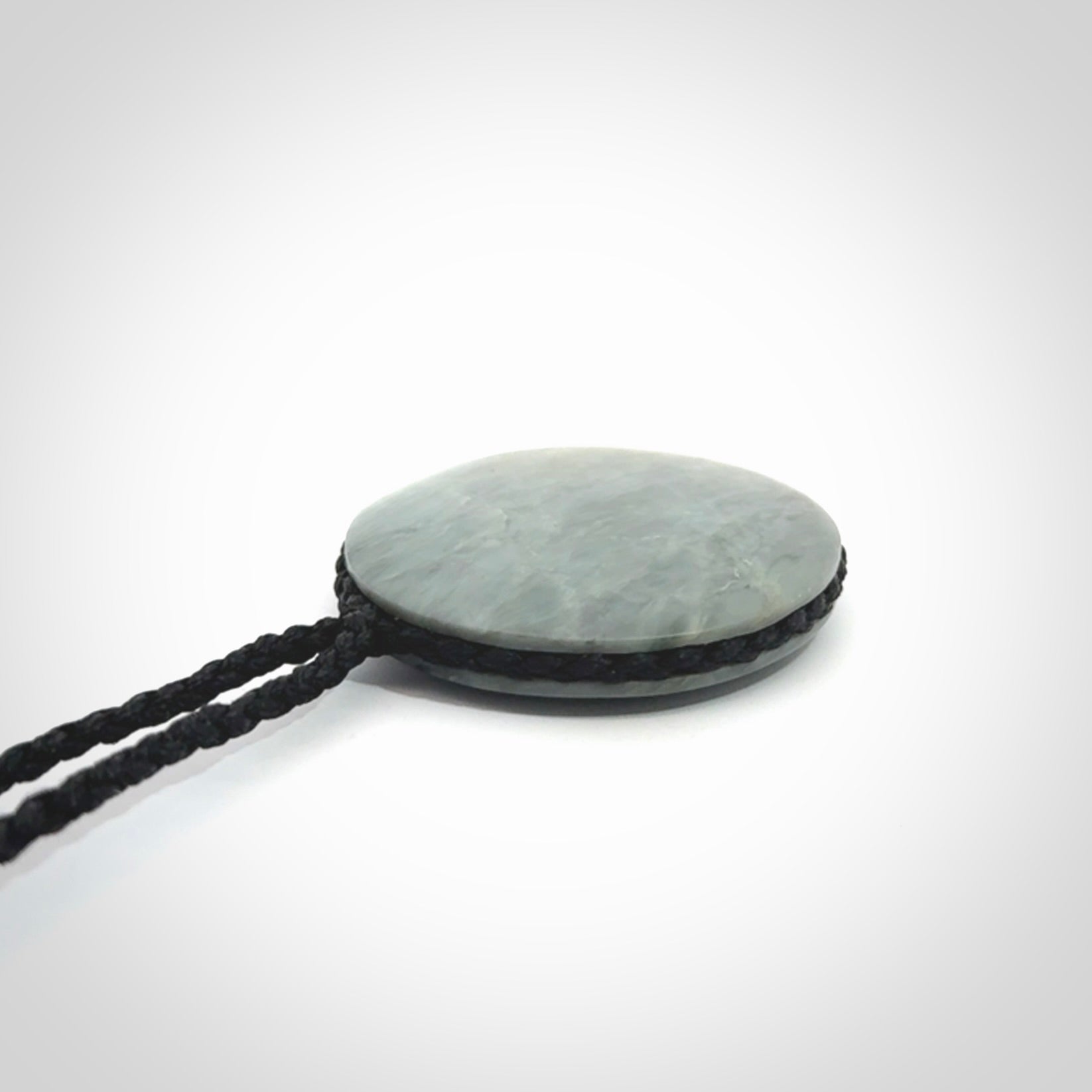 This piece is a contemporary disc pendant hand carved in New Zealand jade.