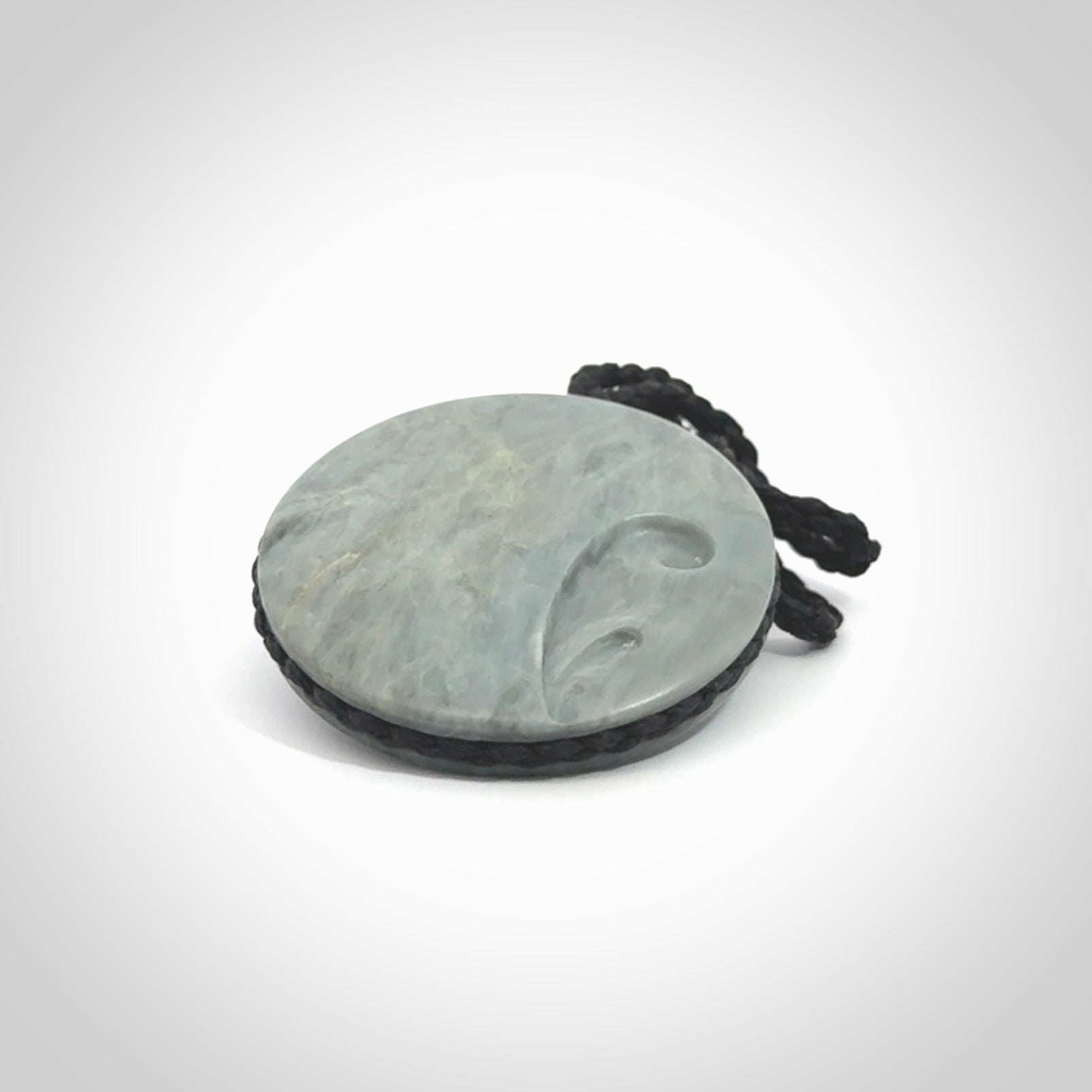 This piece is a contemporary disc pendant hand carved in New Zealand jade.