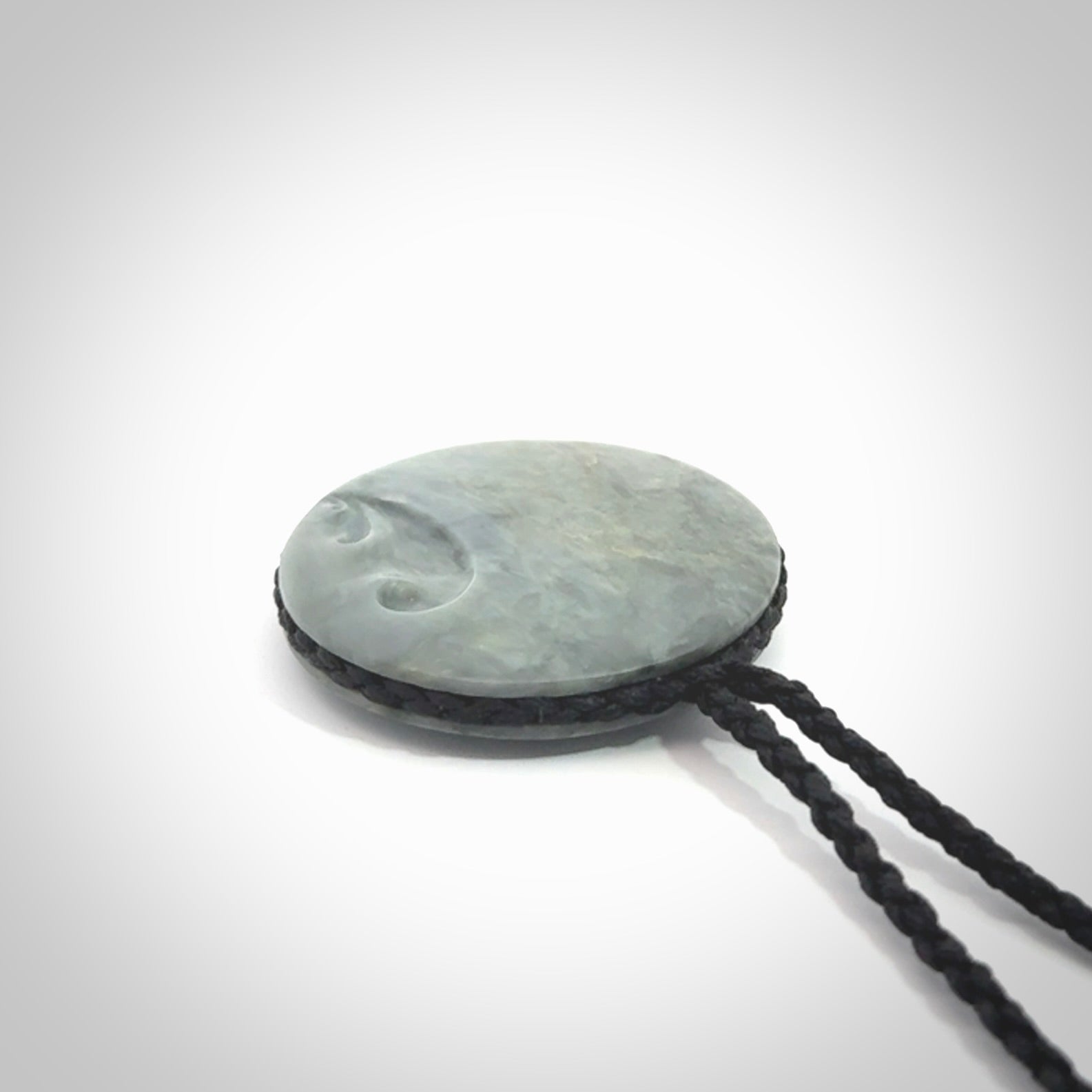 This piece is a contemporary disc pendant hand carved in New Zealand jade.