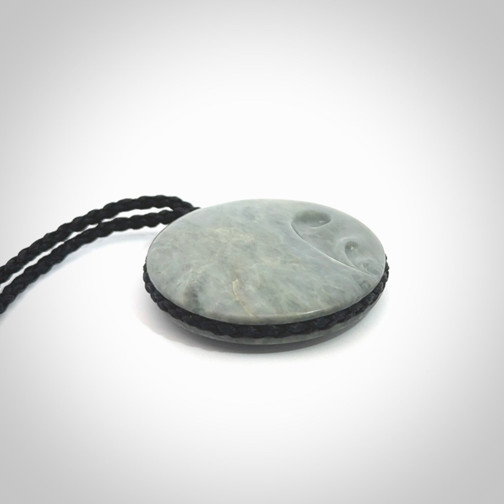 This piece is a contemporary disc pendant hand carved in New Zealand jade.