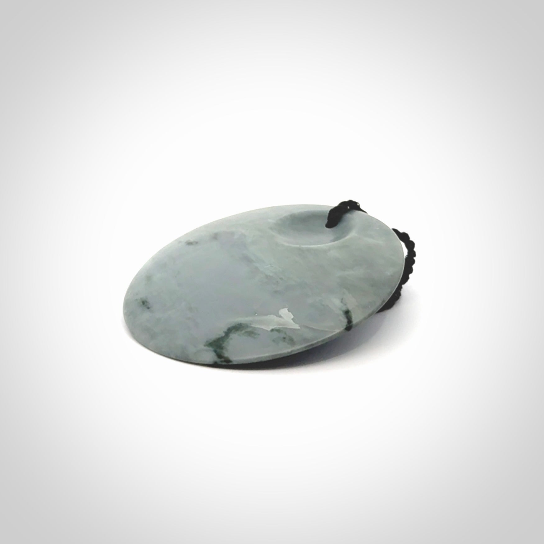 This piece is a contemporary disc pendant hand carved in New Zealand jade.