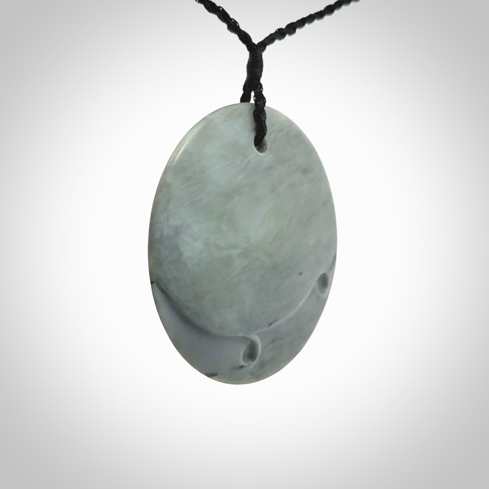 This piece is a contemporary disc pendant hand carved in New Zealand jade.