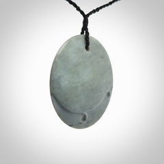 This piece is a contemporary disc pendant hand carved in New Zealand jade.