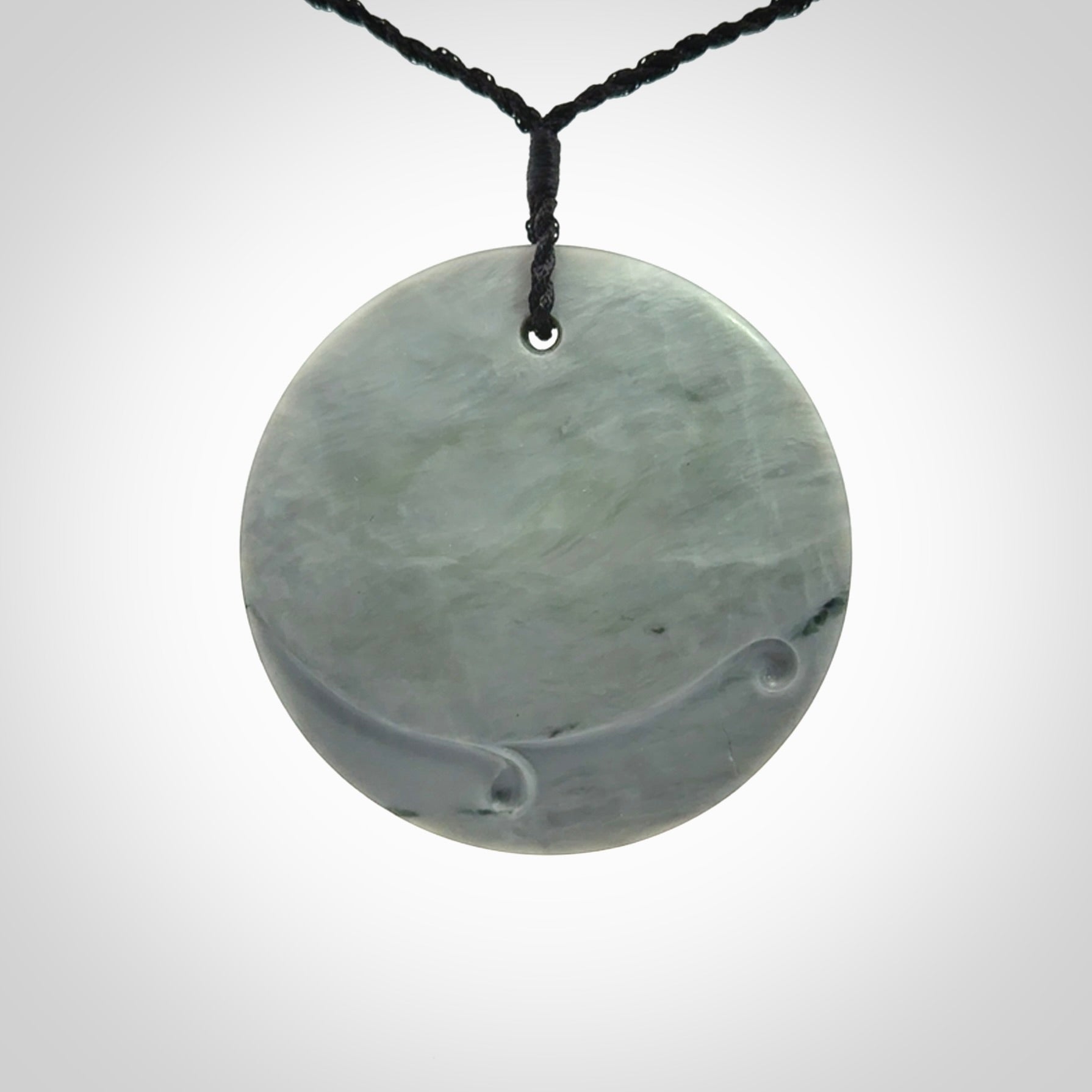 This piece is a contemporary disc pendant hand carved in New Zealand jade.