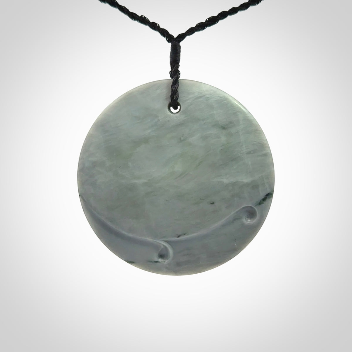 This piece is a contemporary disc pendant hand carved in New Zealand jade.