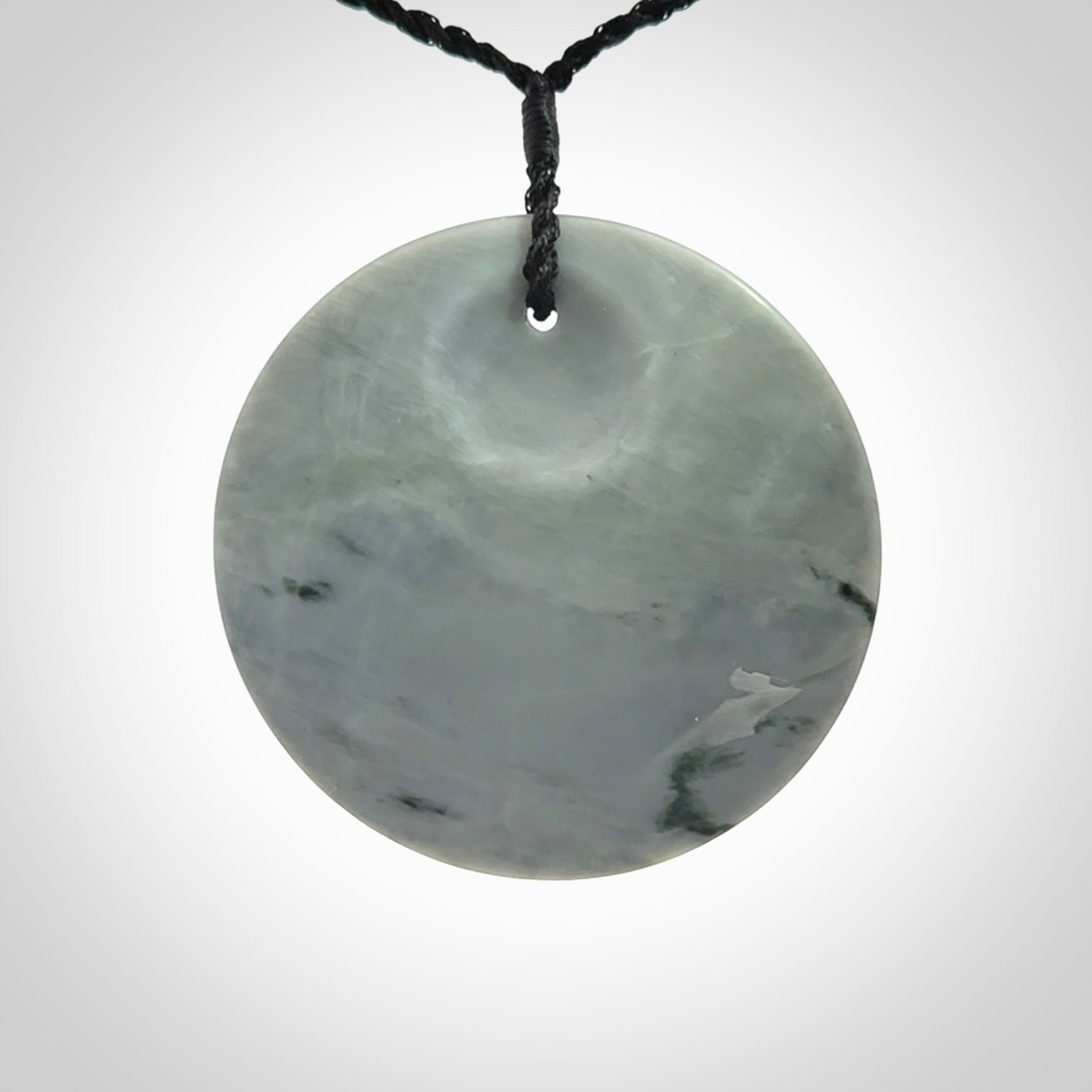 This piece is a contemporary disc pendant hand carved in New Zealand jade.