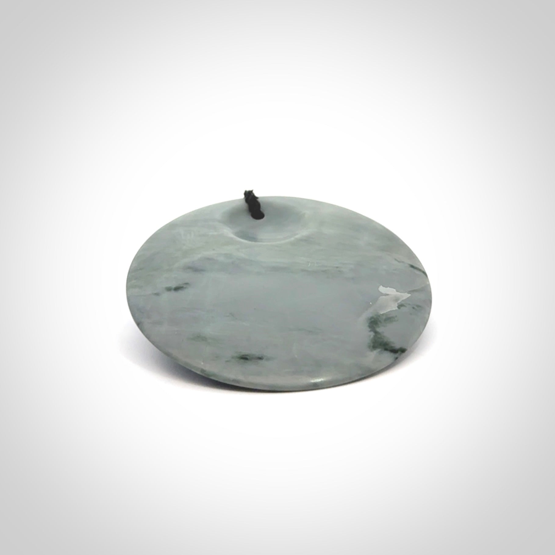 This piece is a contemporary disc pendant hand carved in New Zealand jade.