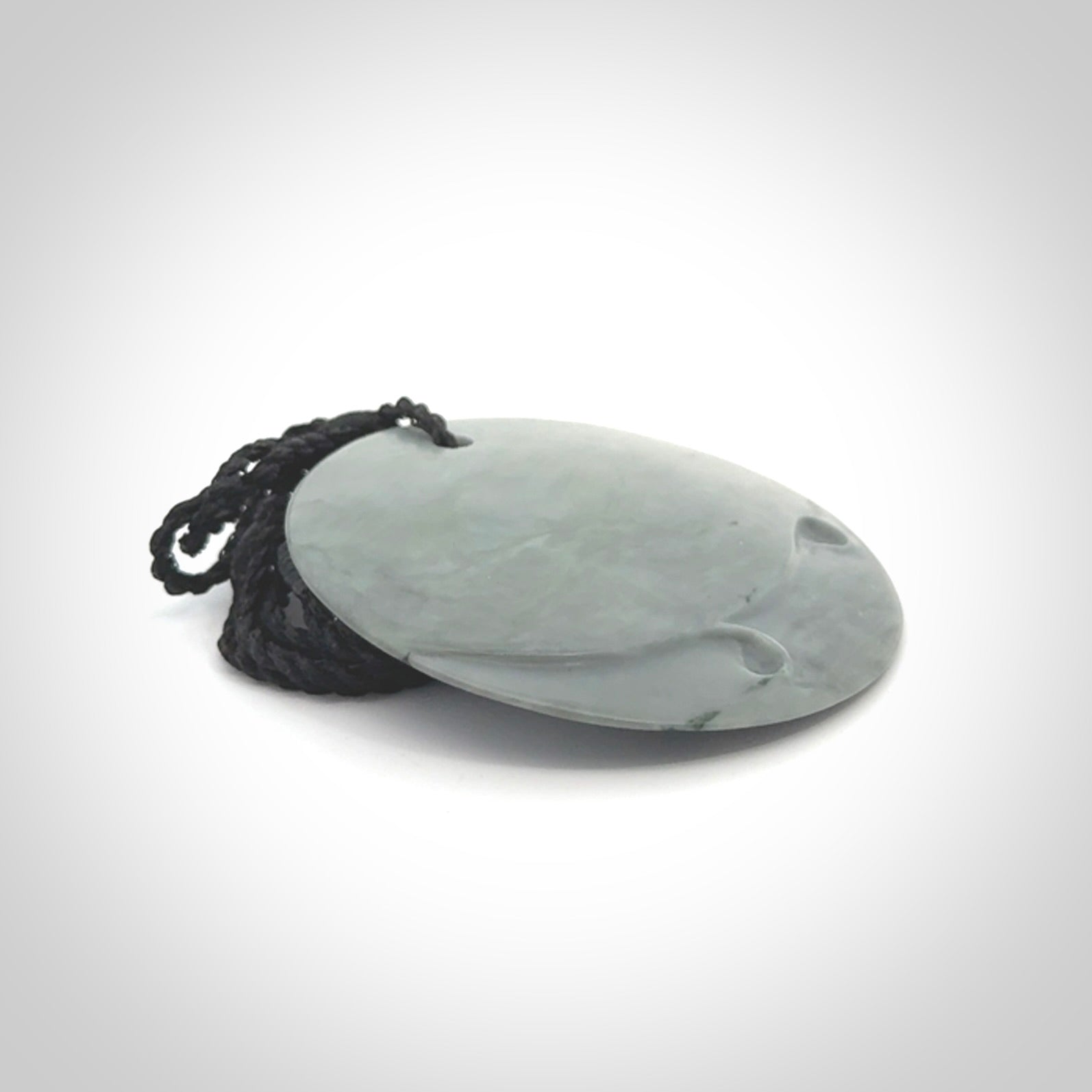 This piece is a contemporary disc pendant hand carved in New Zealand jade.