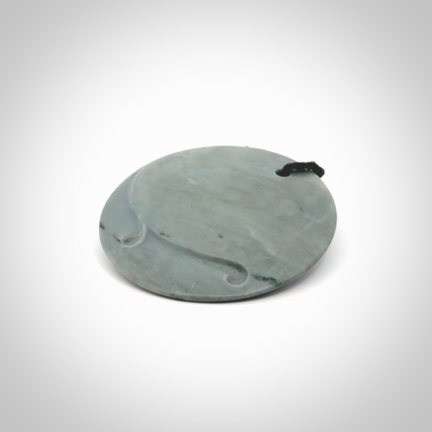 This piece is a contemporary disc pendant hand carved in New Zealand jade.