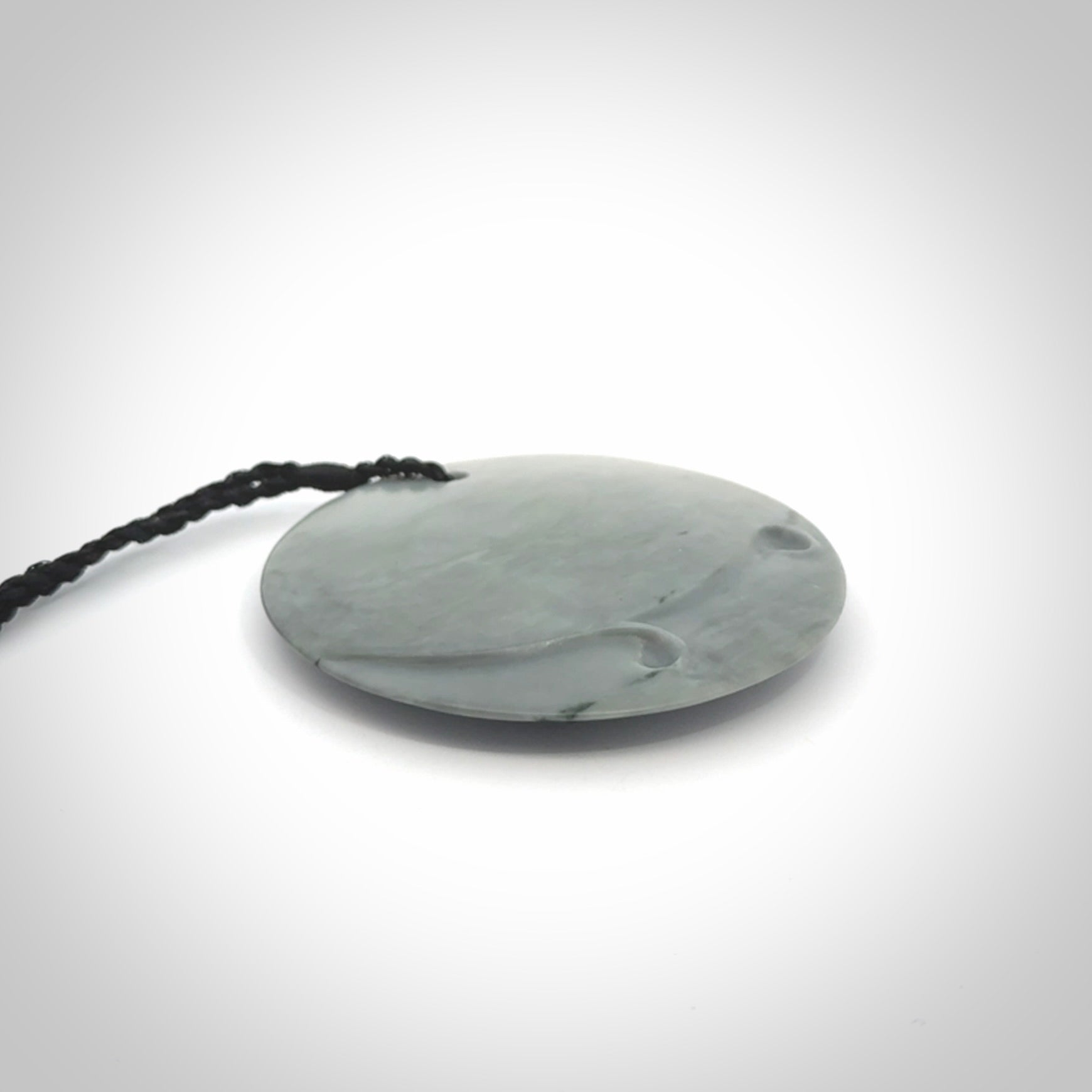 This piece is a contemporary disc pendant hand carved in New Zealand jade.