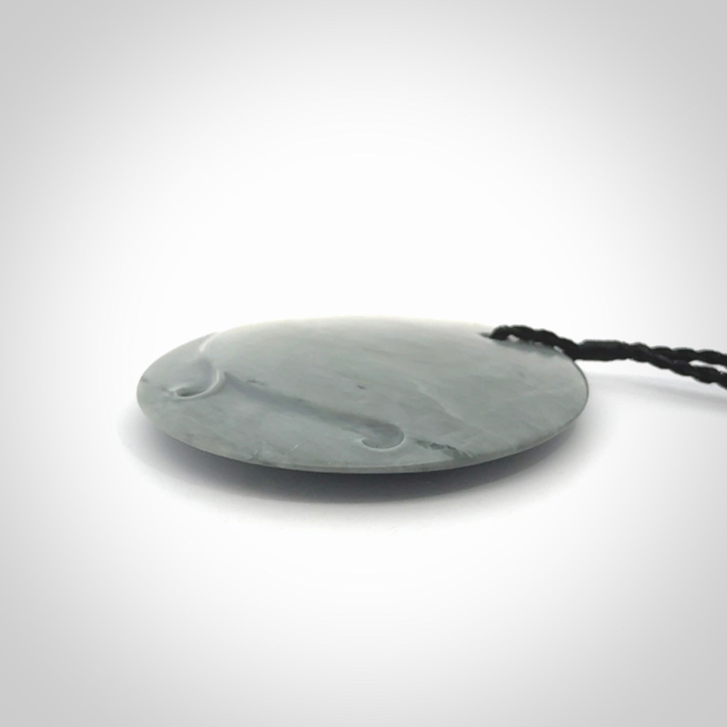 This piece is a contemporary disc pendant hand carved in New Zealand jade.