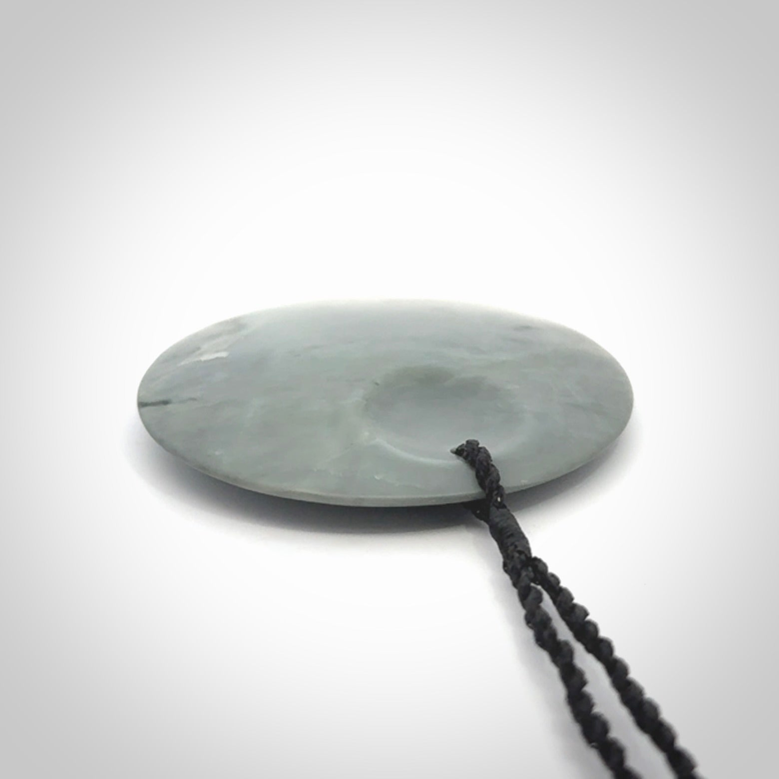 This piece is a contemporary disc pendant hand carved in New Zealand jade.