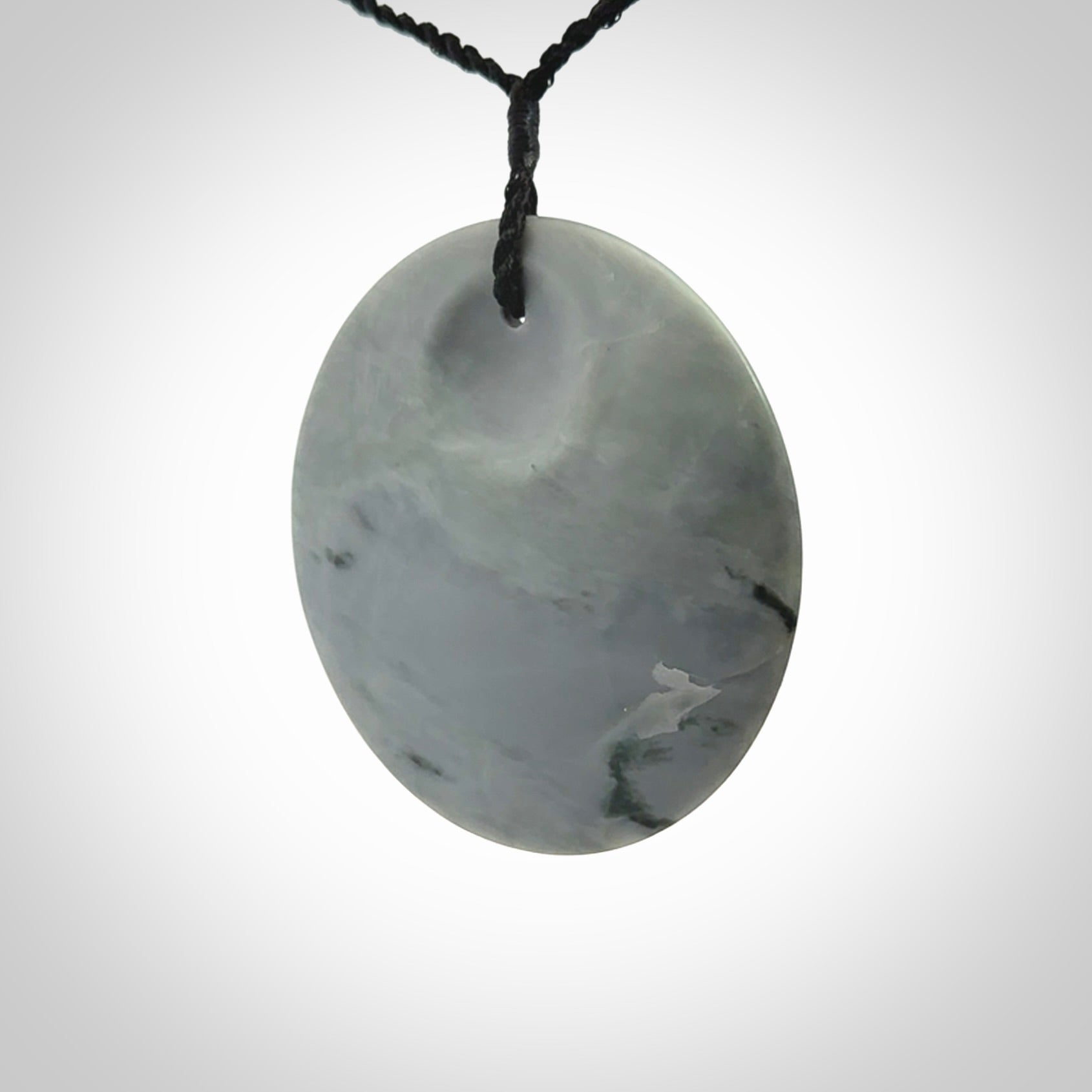 This piece is a contemporary disc pendant hand carved in New Zealand jade.