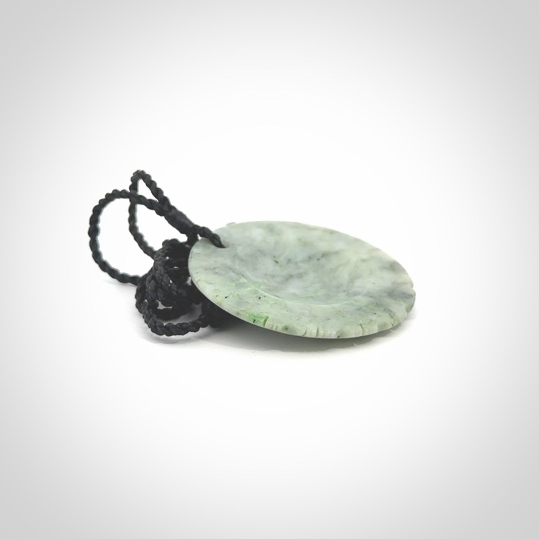 This piece is a contemporary disc pendant hand carved in New Zealand jade.