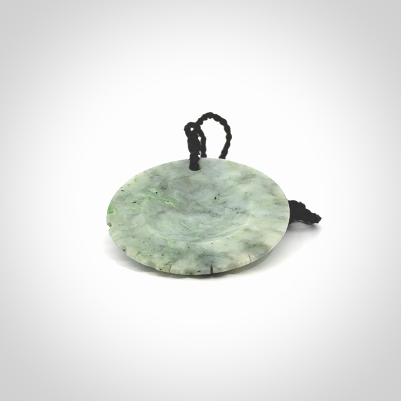 This piece is a contemporary disc pendant hand carved in New Zealand jade.