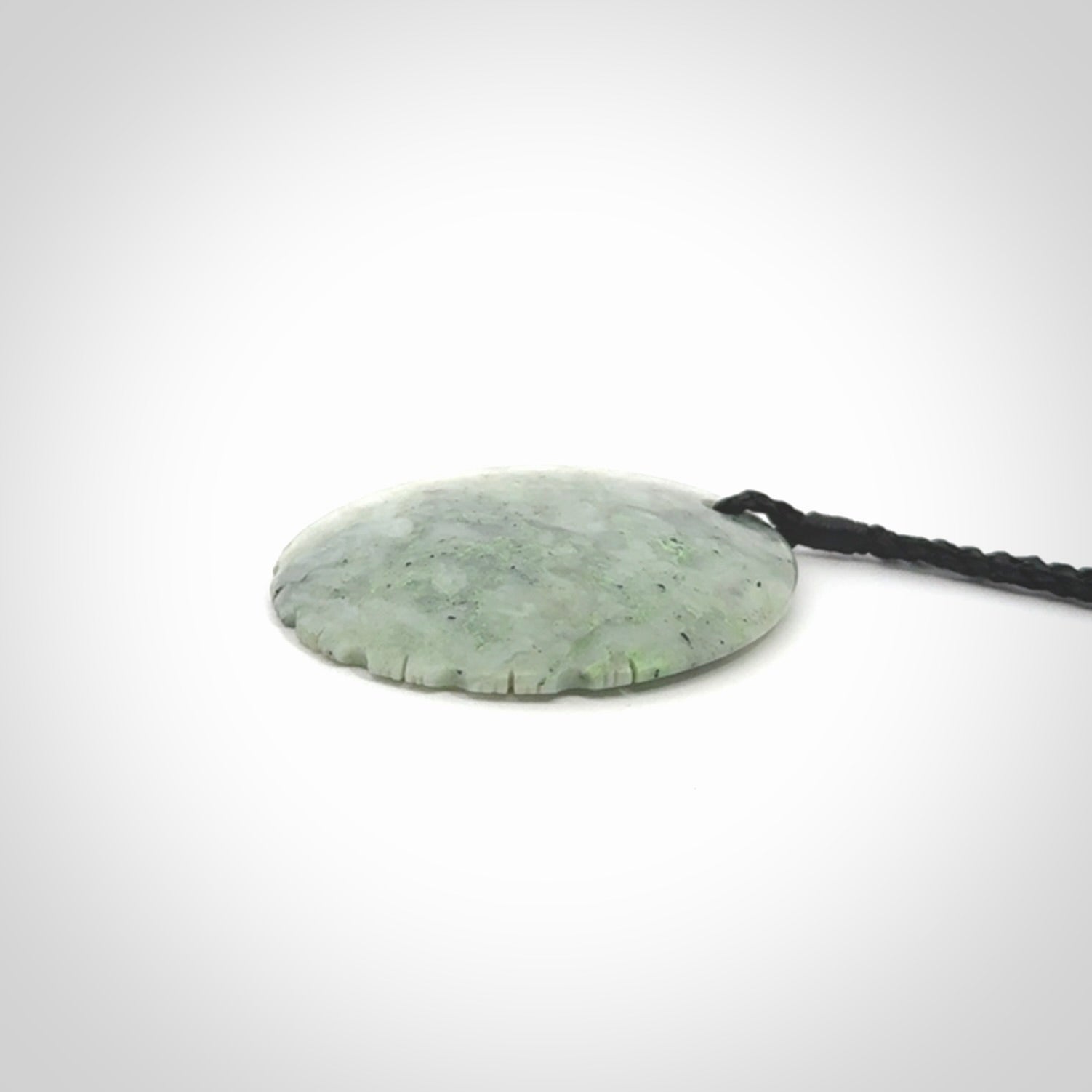 This piece is a contemporary disc pendant hand carved in New Zealand jade.