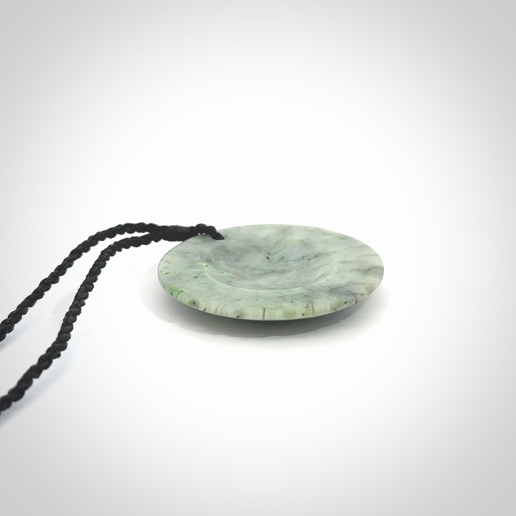 This piece is a contemporary disc pendant hand carved in New Zealand jade.