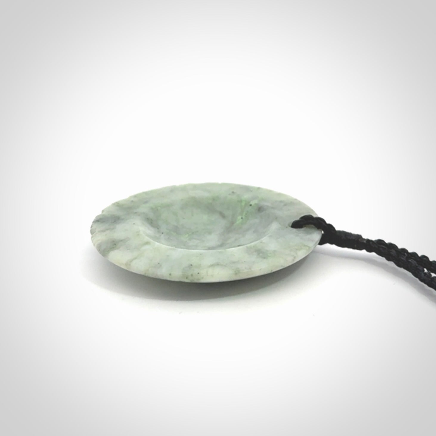 This piece is a contemporary disc pendant hand carved in New Zealand jade.