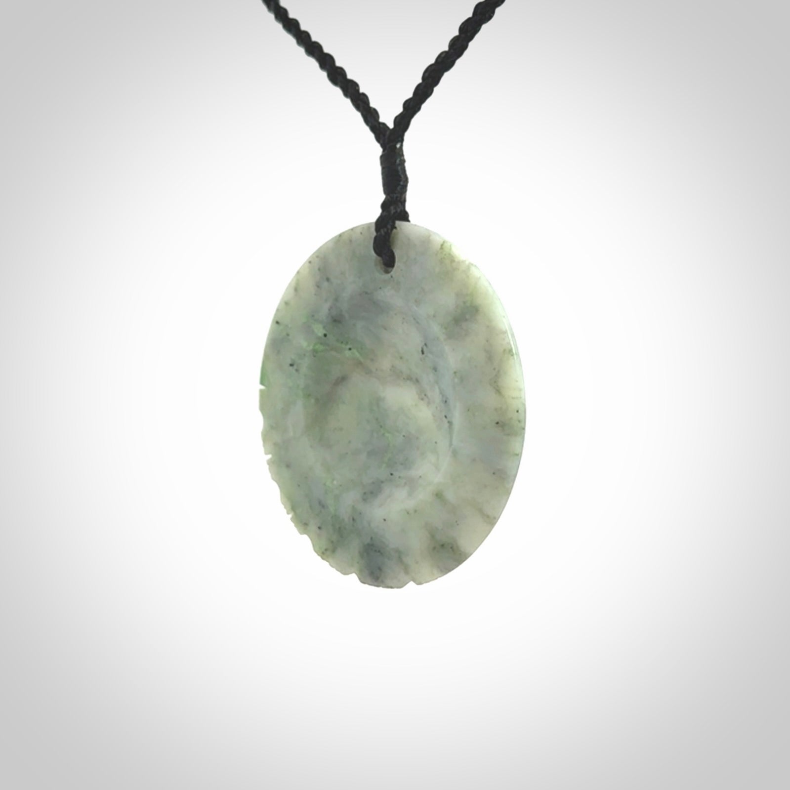 This piece is a contemporary disc pendant hand carved in New Zealand jade.