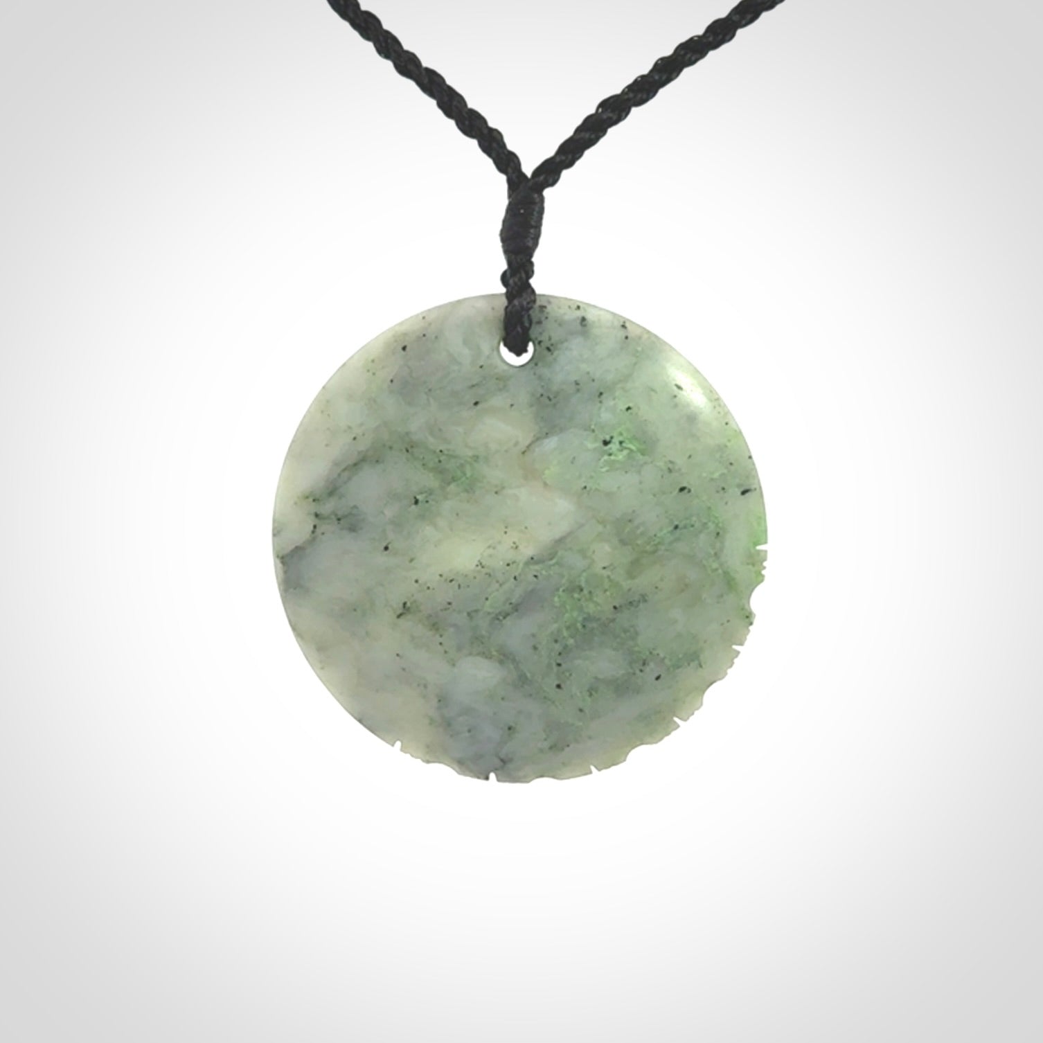 This piece is a contemporary disc pendant hand carved in New Zealand jade.