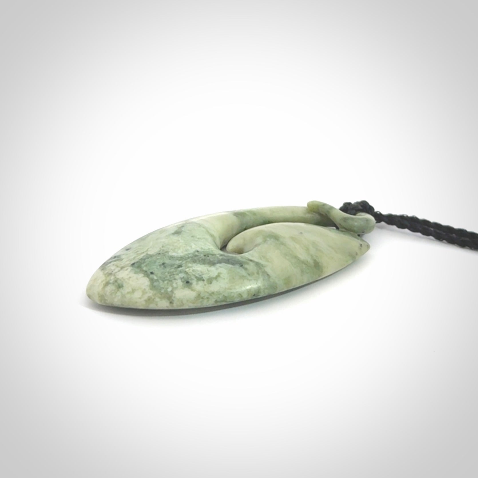A hand carved medium New Zealand Jade Hook, Matau, necklace. The cord is adjustable
