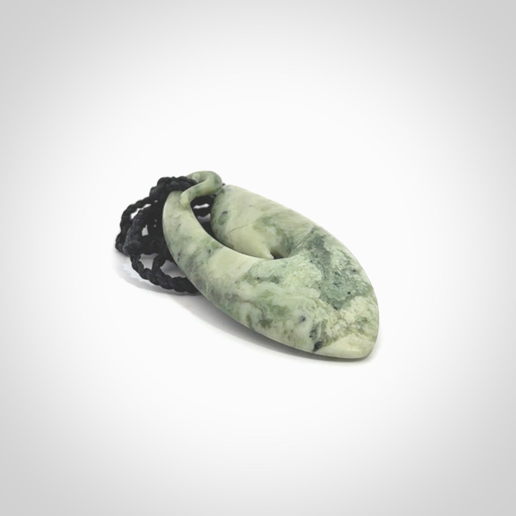 A hand carved medium New Zealand Jade Hook, Matau, necklace. The cord is adjustable