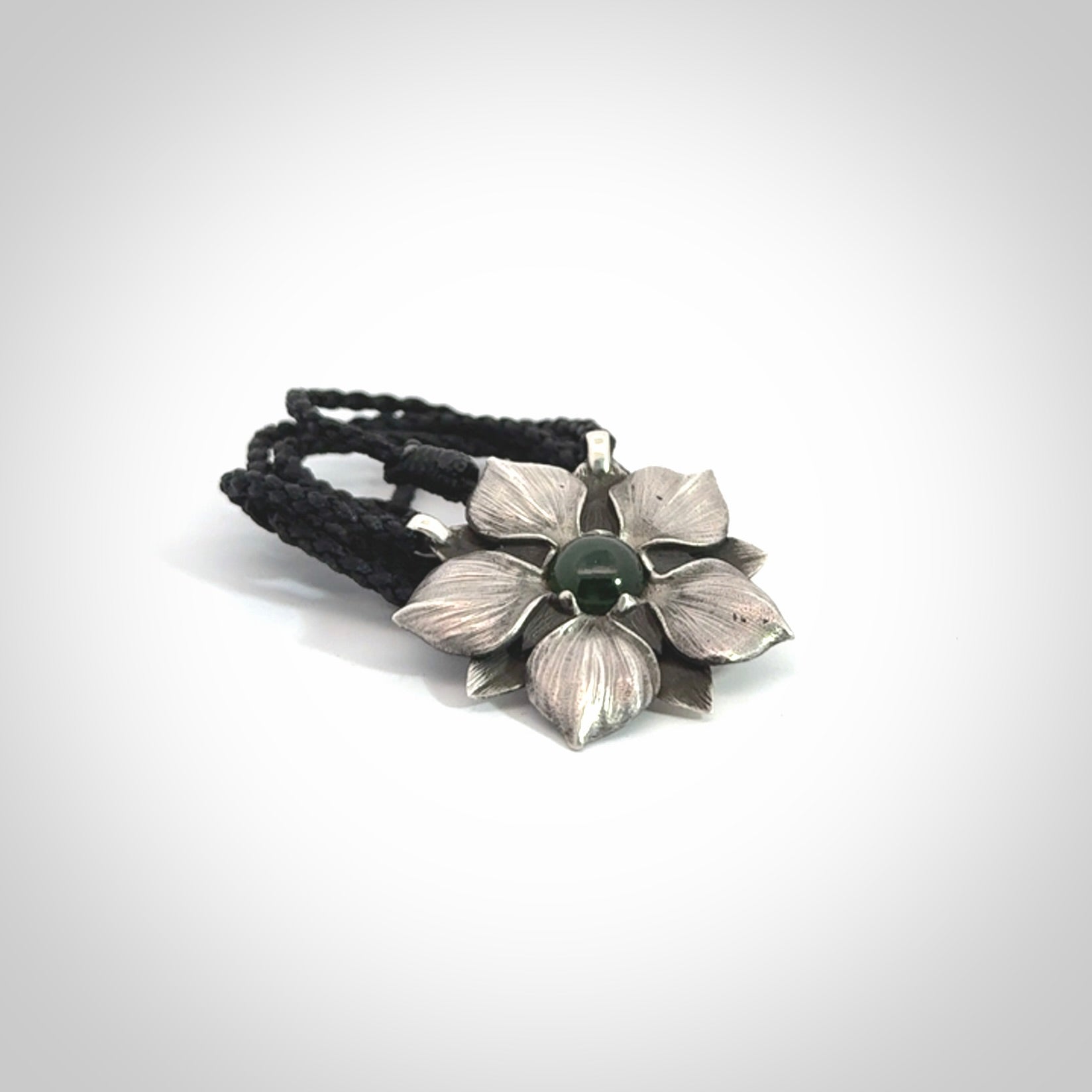 This is a hand carved Sterling Silver Manuka Flower pendant with New Zealand Jade insert. This is a medium sized necklace and is provided with an adjustable black cord.
