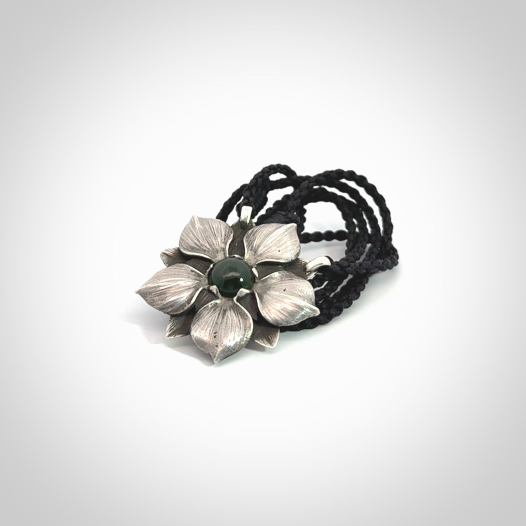 This is a hand carved Sterling Silver Manuka Flower pendant with New Zealand Jade insert. This is a medium sized necklace and is provided with an adjustable black cord.
